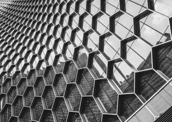Black and white image of a modern building facade with a geometric hexagonal pattern.