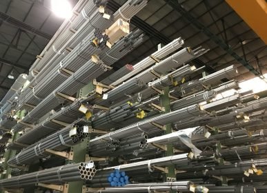 Wide view of metal pipes stacked in an industrial warehouse, emphasizing storage and organization.